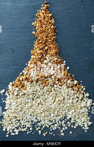 Un sano mix di cereali e farina di avena on dark sassoso scheda sopra vintage sfondo di legno, vista dall'alto, close-up, il fuoco selettivo. Figura astratta in sha Foto Stock