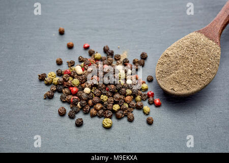 Pepe cinese, Pepe Sichuan nel cucchiaio di legno su ardesia nera lastra di pietra con spazio di copia Foto Stock