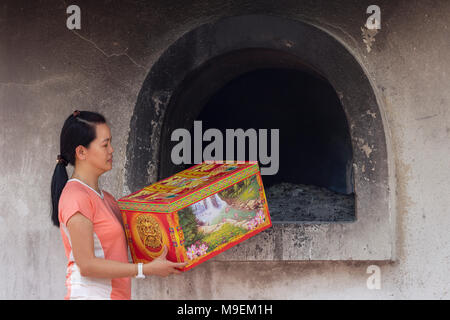 Kuala Lumpur 02 Mac 2018 - donna asiatica permanente al bruciatore di preghiera casa nei pressi di un cimitero, questo è un cinese Toaish offerta rituale spirito i soldi per la a Foto Stock