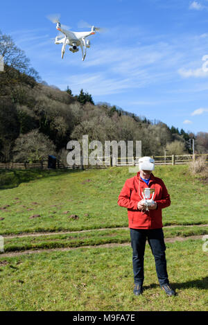 Wye Valley, Monmouthshire, Regno Unito. 25 marzo 2018: l'uomo in escursionismo vestiti, volare un quadcopter drone utilizzando FPV gli occhiali di protezione Foto Stock