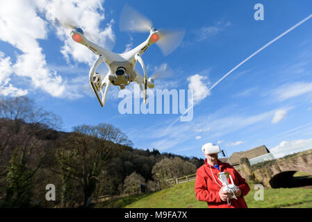 Wye Valley, Monmouthshire, Regno Unito. 25 marzo 2018: l'uomo in escursionismo vestiti, volare un quadcopter drone utilizzando FPV gli occhiali di protezione Foto Stock