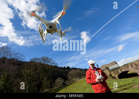 Wye Valley, Monmouthshire, Regno Unito. 25 marzo 2018: l'uomo in escursionismo vestiti, volare un quadcopter drone utilizzando FPV gli occhiali di protezione Foto Stock