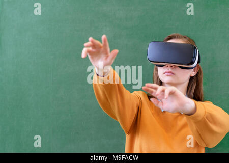 Adolescente studentessa indossando occhiali per realtà virtuale in aula a scuola. Metodi di insegnamento innovativi. Il concetto di istruzione. Foto Stock