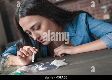 Giovani donne tossicodipendenti problemi sociali seduta a tavola lo sniffing cocain euforia occhi chiusi close-up Foto Stock