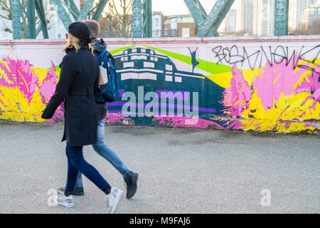 Persone che camminano da, pedoni a piedi passato, Arte di strada, graffiti su un ponte in Primrose Hill, Londra UK vita quotidiana vita giovane a piedi i giovani della gioventù Foto Stock