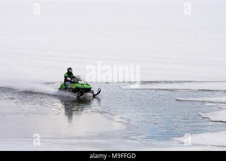 In Snowmobile racing attraverso una patch aperto di acqua sul Lago Pleasant, NY nelle Montagne Adirondack, con copia spazio. Foto Stock