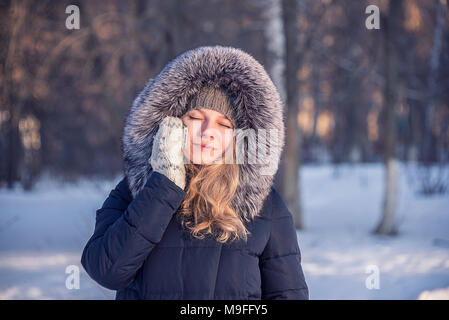 Ragazza parla al telefono per strada, d'inverno il vestito di una pelliccia, congelate le mani Foto Stock