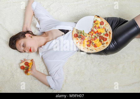 Overeat donna con pezzi di pizza su sfondo bianco Foto Stock