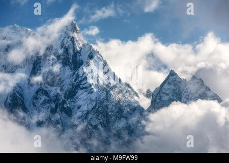 Majestical scena con montagne con cime innevate in nuvole in Nepal. Paesaggio con belle e alte rocce e drammatico cielo nuvoloso nella soleggiata giornata splendente. Foto Stock