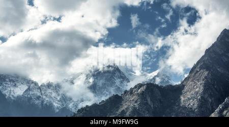 Majestical scena con montagne con cime innevate in nuvole in Nepal. Paesaggio colorato con belle e alte rocce e drammatico cielo nuvoloso al tramonto. N Foto Stock