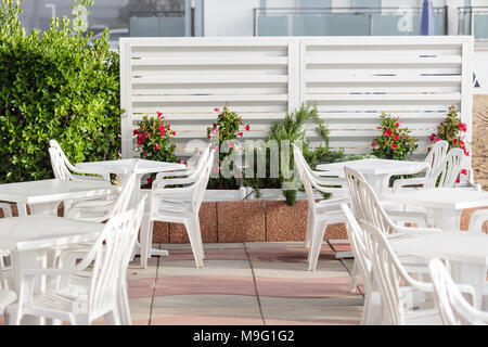 Terrazza con sedie e la plastica bianca tabella accanto al mare. La spiaggia di Lido di Jesolo al Mare Adriatico in una bella giornata d'estate Italia Foto Stock