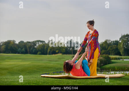 Massaggio tailandese esercita sul parco prato. Due donne facendo il massaggio thai formazione. Foto Stock