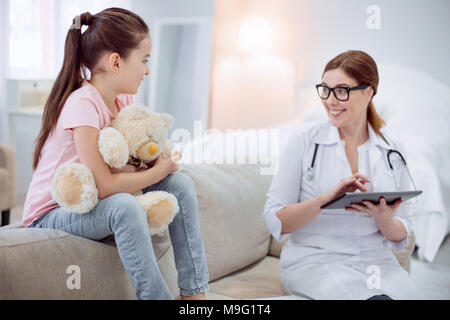 Gioiosa medico donna comunicante con la ragazza Foto Stock