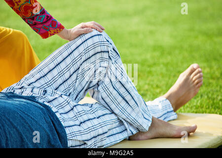 L uomo per le gambe dei pantaloni, vicino. Sdraiato sul tappeto nel parco. Foto Stock