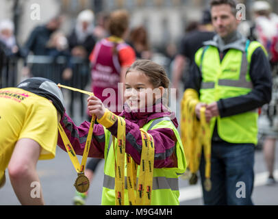 Londra, Regno Unito. Xxv Marzo 2018. Bambina aiutando dare medaglie a Londra - La Mezza Maratona di credito: Keith Donegan/Alamy Live News Foto Stock