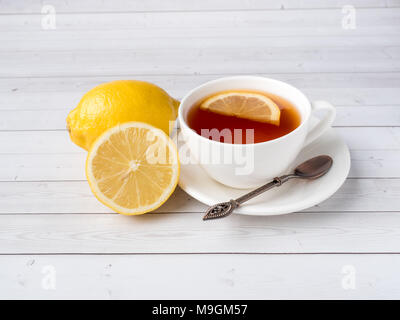 A base di erbe tè nero in una tazza bianca, il miele in un vaso di limone fresco bianco su sfondo di legno. Foto Stock