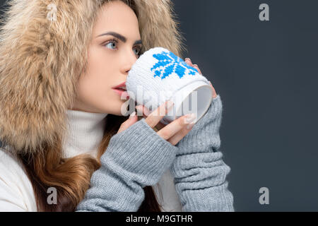 Bella donna nel cappello di pelliccia e abbigliamento invernale, isolato su grigio Foto Stock