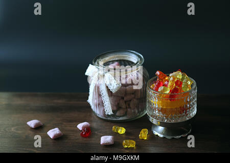 La marmellata di arance in un vaso sul tavolo. Caramelle in una ciotola su una ba nero Foto Stock