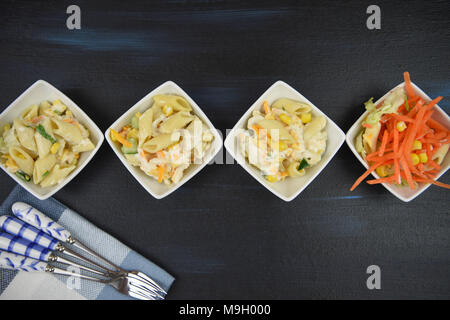 Laici piatta con una linea bianca di piatti a base di insalata di pasta Foto Stock