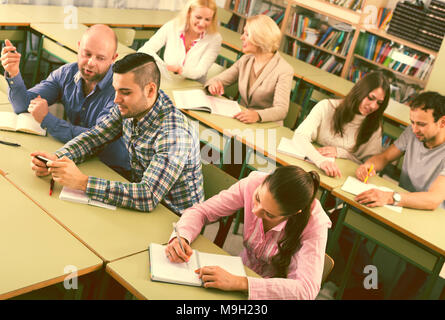 Adulti professionisti russi tenendo note alla sessione di formazione per i dipendenti Foto Stock