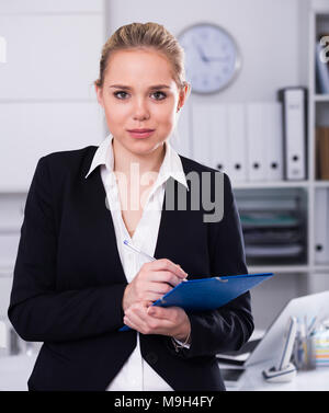 Segretario attraente la scrittura di istruzioni al lavoro in ufficio Foto Stock