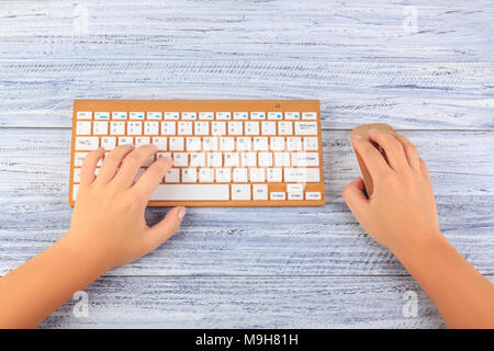 Vista dall'alto in mani femminili nei pressi di oro wireless tastiera e mouse Foto Stock