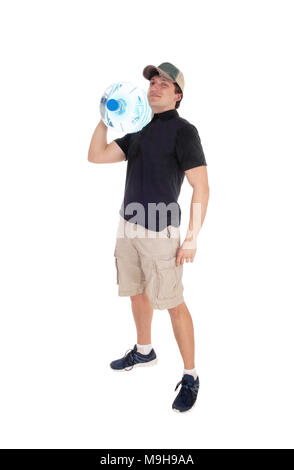 Un giovane ragazzo di consegna in pantaloncini corti che porta un grande vaso di acqua su questo spallamento sorridente, isolato per sfondo bianco Foto Stock