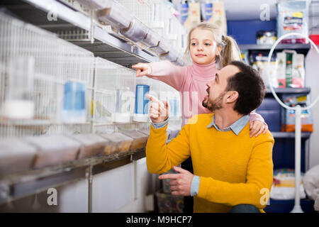 Giovani papà con sua figlia ammirare diverse specie di uccelli in un pet shop Foto Stock