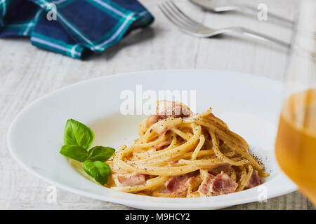 Spaghetti alla carbonara sulla piastra bianca con foglie di basilico Foto Stock