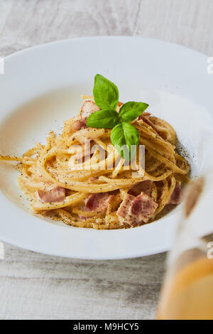 Spaghetti alla carbonara sulla piastra bianca con foglie di basilico Foto Stock