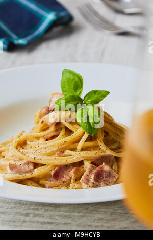 Spaghetti alla carbonara sulla piastra bianca con foglie di basilico Foto Stock