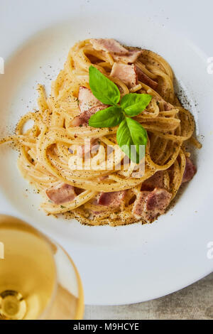 Spaghetti alla carbonara sulla piastra bianca con foglie di basilico Foto Stock