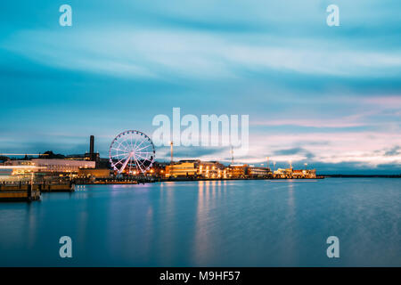 Helsinki, Finlandia. Vista del terrapieno con ruota panoramica Ferris in sera illuminazione notturna. Foto Stock