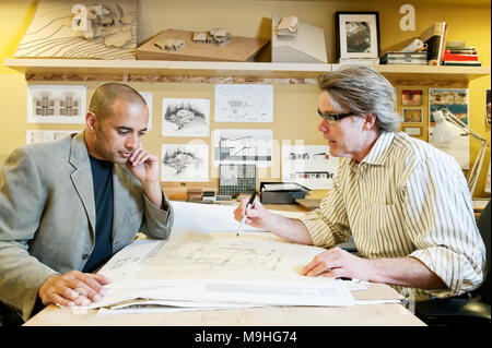 Un multi-etnico team di due architetti maschio lavorando su piani per una nuova casa in un ufficio dell'architetto. Foto Stock