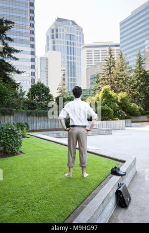 Imprenditore prendendo una pausa a piedi nudi in un centro parco della città. Foto Stock