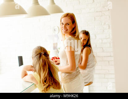 La madre e le figlie preparazione frullato shealthy nella cucina moderna Foto Stock