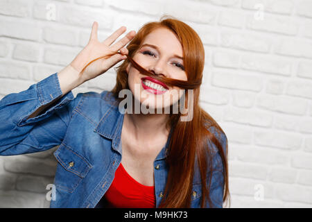 Le espressioni del viso dei giovani Redhead Donna su un muro di mattoni Foto Stock