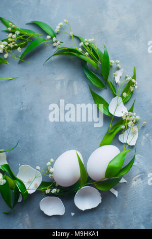 Vingette cerchio bianco con le uova di Pasqua, decorativo foglie verdi e fiori di primavera. Cucina organica concetto con copia spazio. Foto Stock