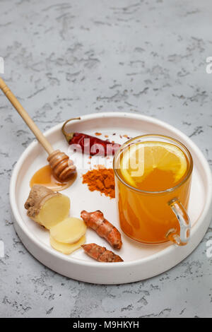 Mattina detox drink curcuma in vetro su un cemento grigio Sfondo. spazio copia Foto Stock