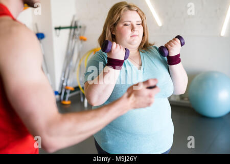 Donna obesa che lavora fuori con pesi Foto Stock