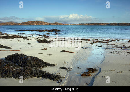 Un assolato pomeriggio di febbraio. Nord est attraverso St Ronan;'s Bay e il suono di Iona verso Mull. Le alghe, rocce, stream e sabbia. Iona Foto Stock