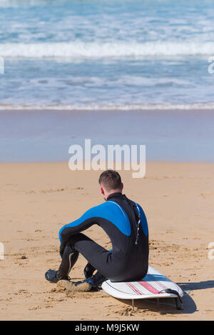 Regno Unito surf - un surfista seduta a riposo sulla sua tavola da surf su Fistral Beach in Newquay Cornwall Foto Stock