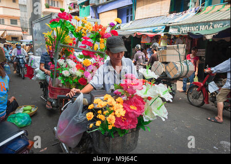 Vietnam colorato mercato, un portiere porta una fornitura di fiori freschi al mercato di Binh Tay, nel quartiere di Cholon, a Saigon, a Ho Chi Minh City, Vietnam Foto Stock