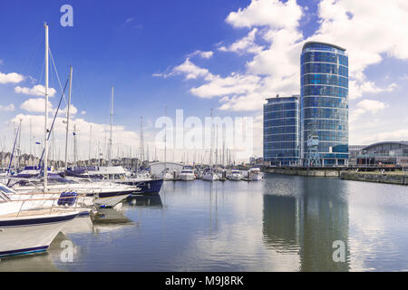 Barche e yacht ormeggiati a Chatham maritime marina nel Kent con 2 edifici alti che si affaccia sulla marina Foto Stock