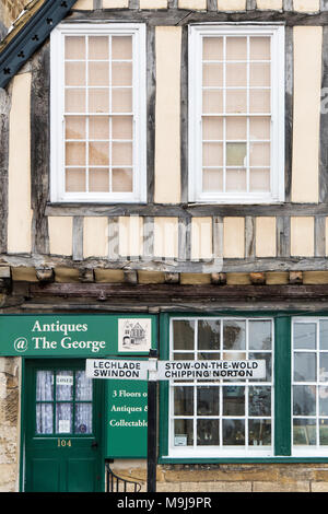 Stow on the wold, Chipping Norton, Lechlade e Swindon cartello stradale di fronte alla George antiquariato edificio centrale a Burford, Cotswolds, Inghilterra Foto Stock