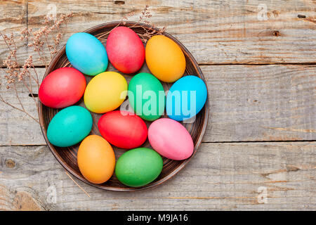 Piastra con colorate uova di pasqua sulla tavola di legno Foto Stock