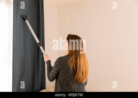 Una giovane donna caucasica vacua un pavimento della cucina usando un aspirapolvere  verticale senza filo, o scopa elettrica. La cameriera sta pulendo il cuoco  degli ostelli Foto stock - Alamy