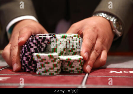 Giocatore al tavolo da gioco pusing grande pila di chip Foto Stock