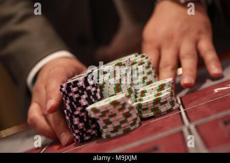 Giocatore al tavolo da gioco pusing grande pila di chip Foto Stock