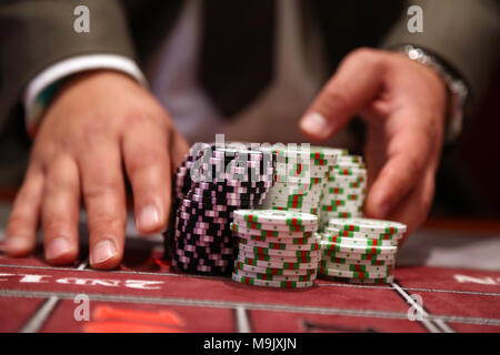 Giocatore al tavolo da gioco pusing grande pila di chip Foto Stock